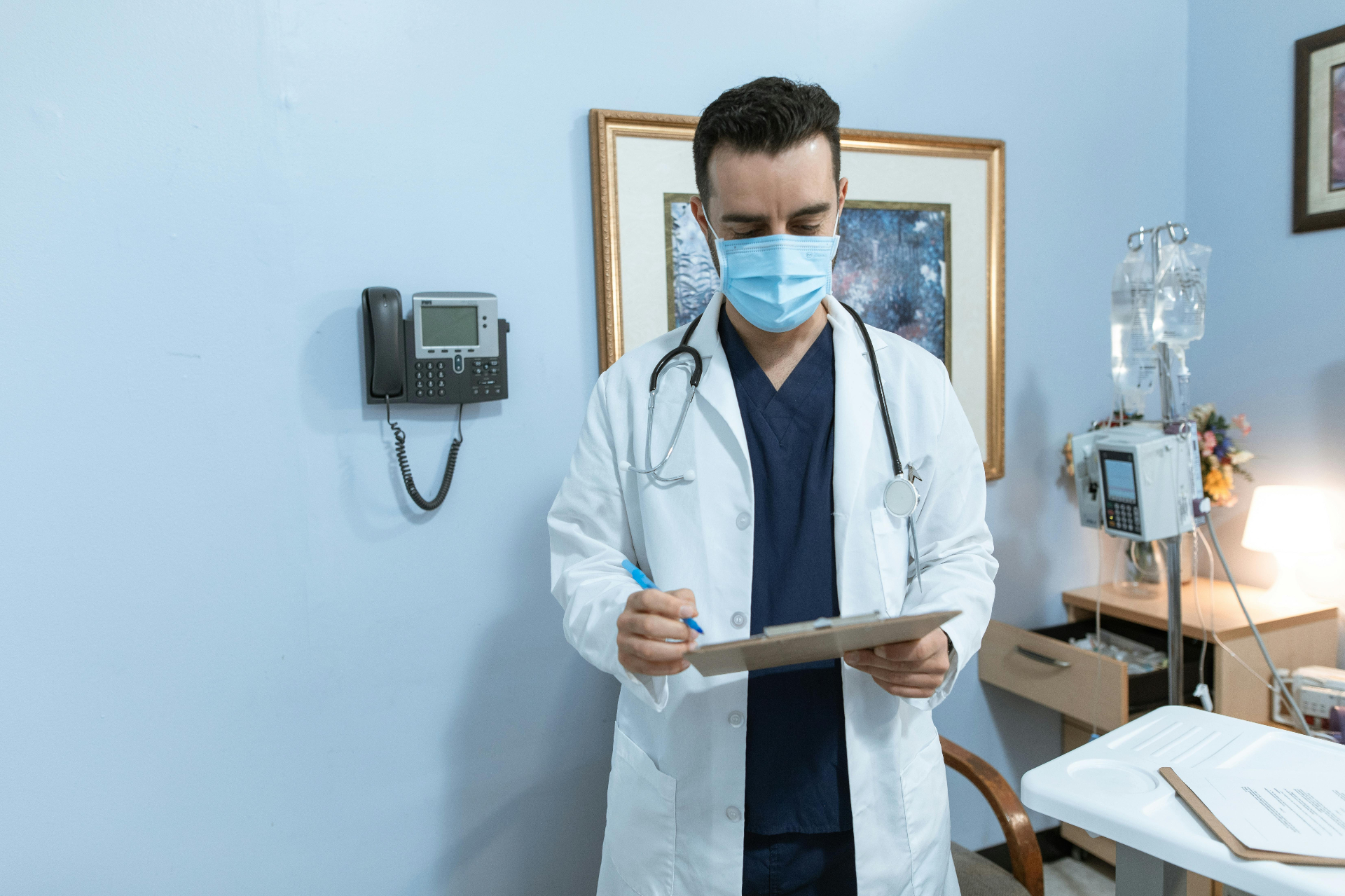 Clinician reviewing patient chart next to a desk phone in an exam room